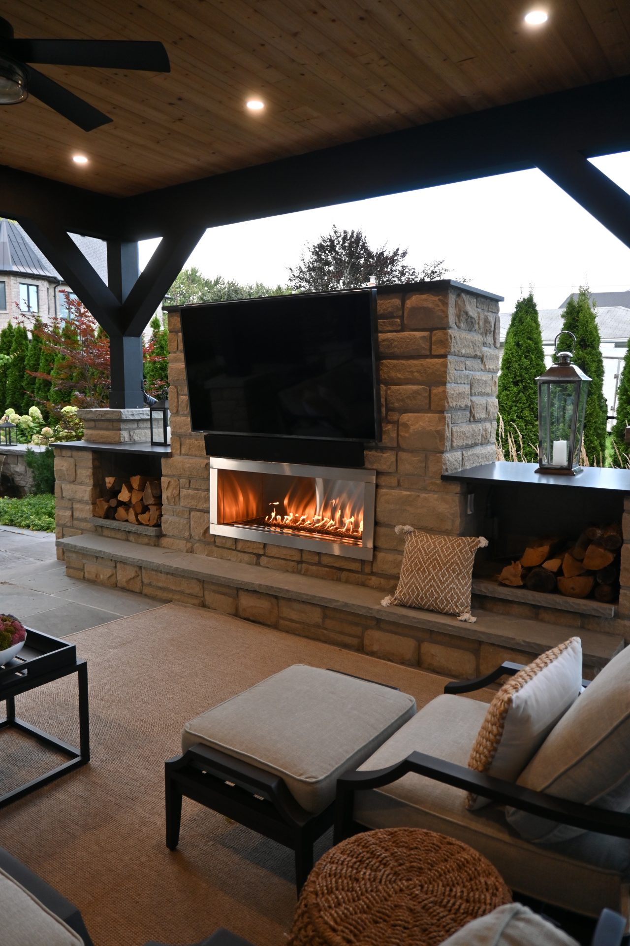 Cozy patio with fireplace and TV under pergola.