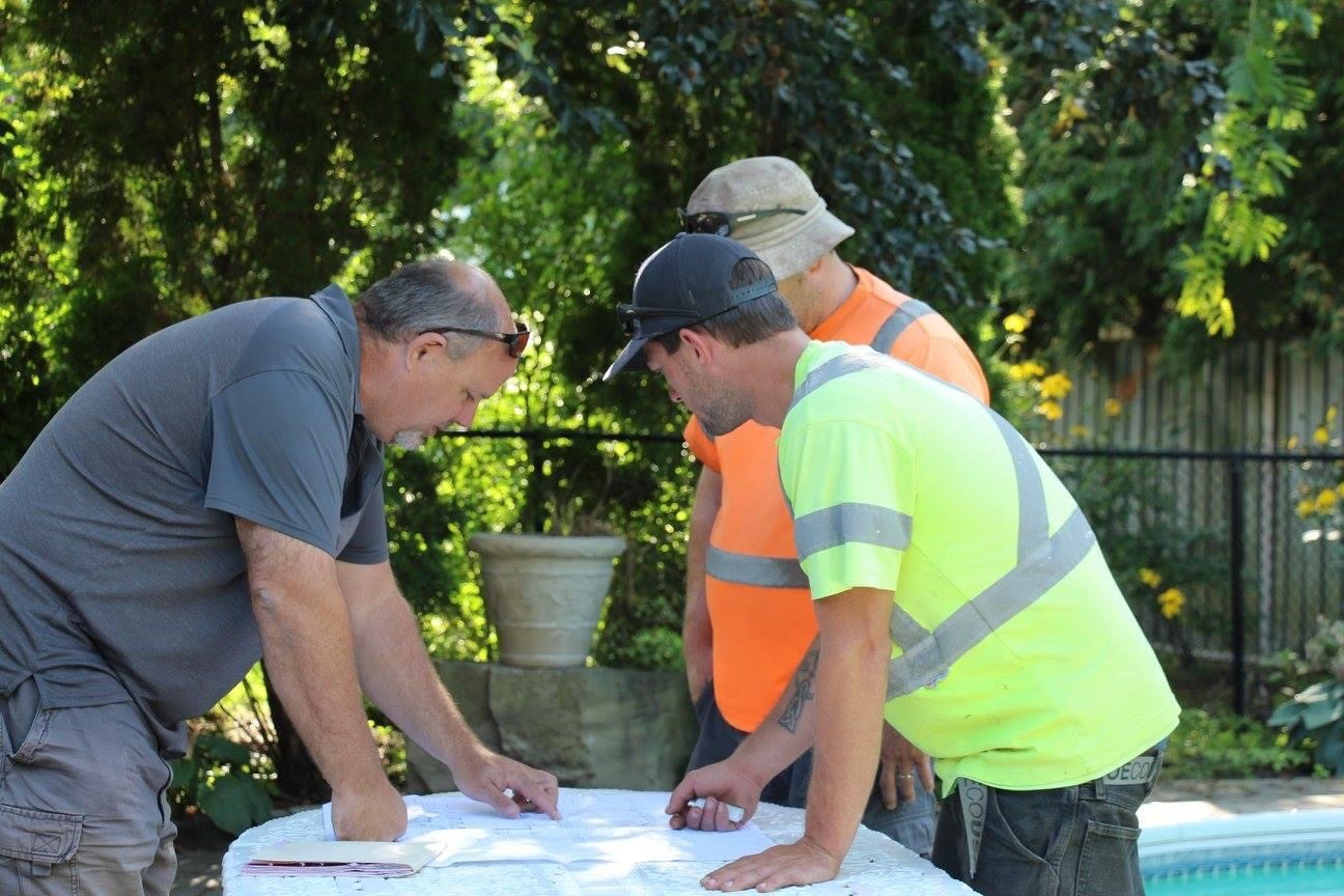Construction workers reviewing plans outdoors.