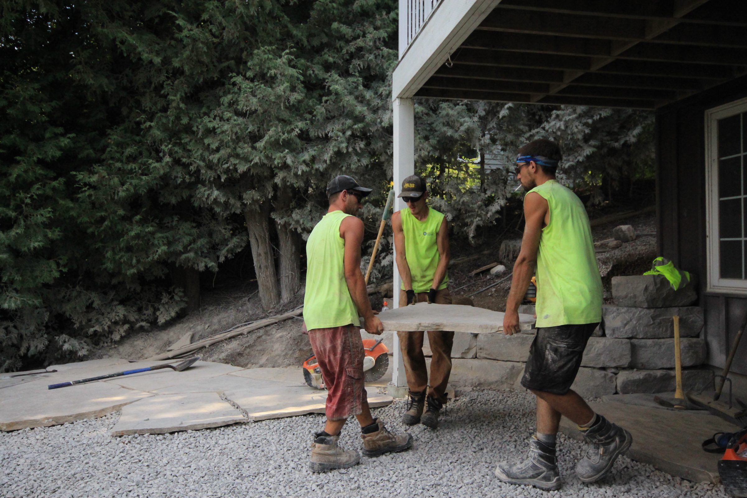 Three workers carry stone under deck