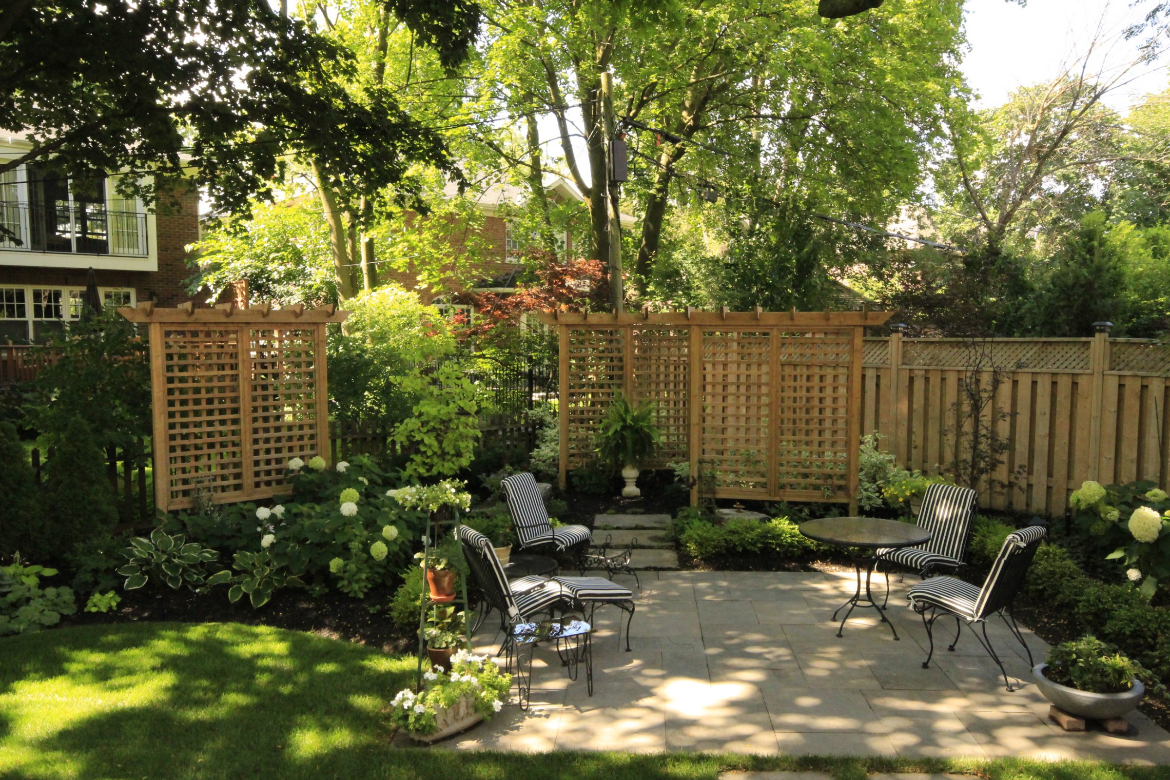 Tranquil backyard garden with wooden fence and chairs.