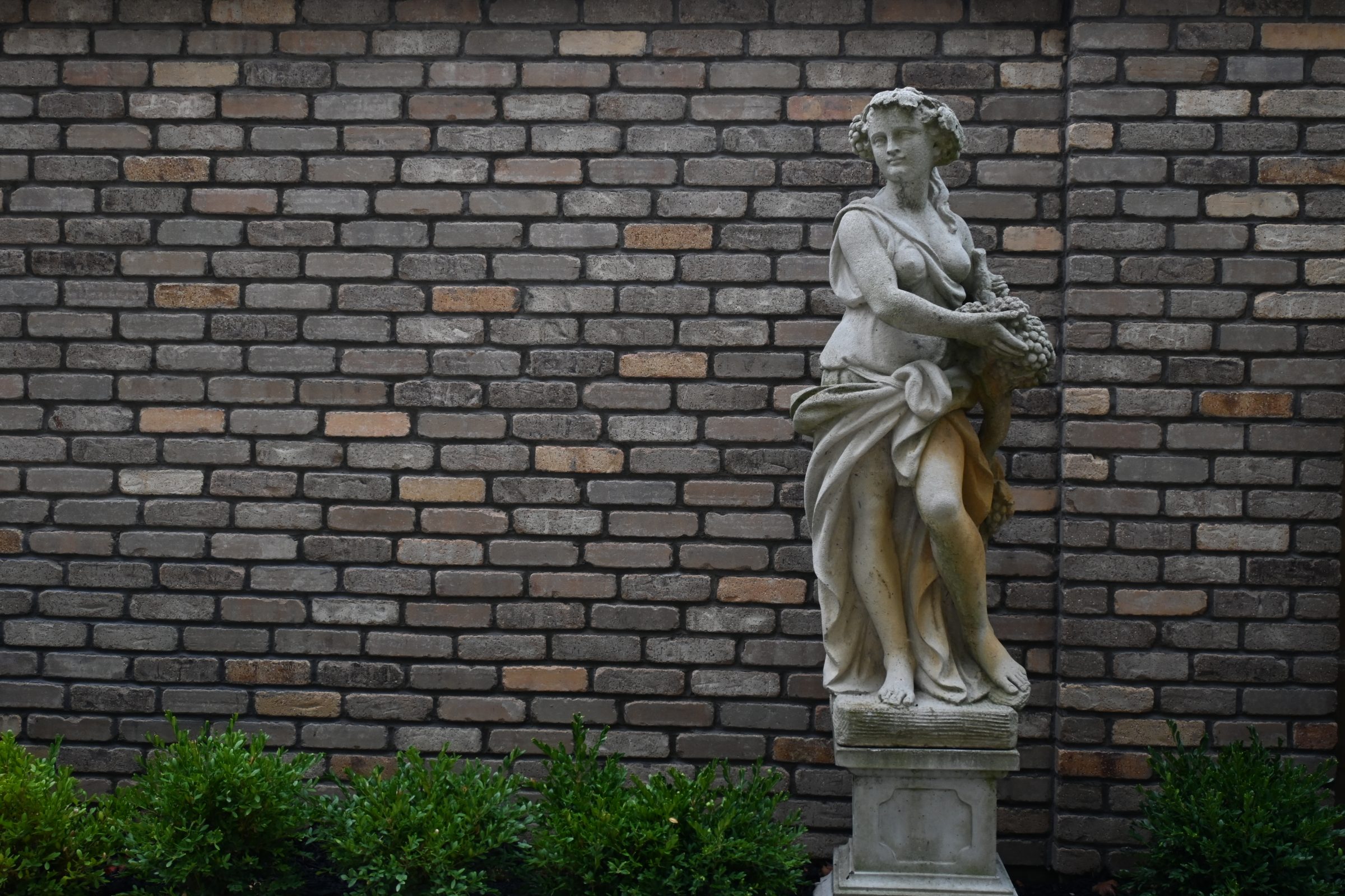 Stone statue of woman against brick wall
