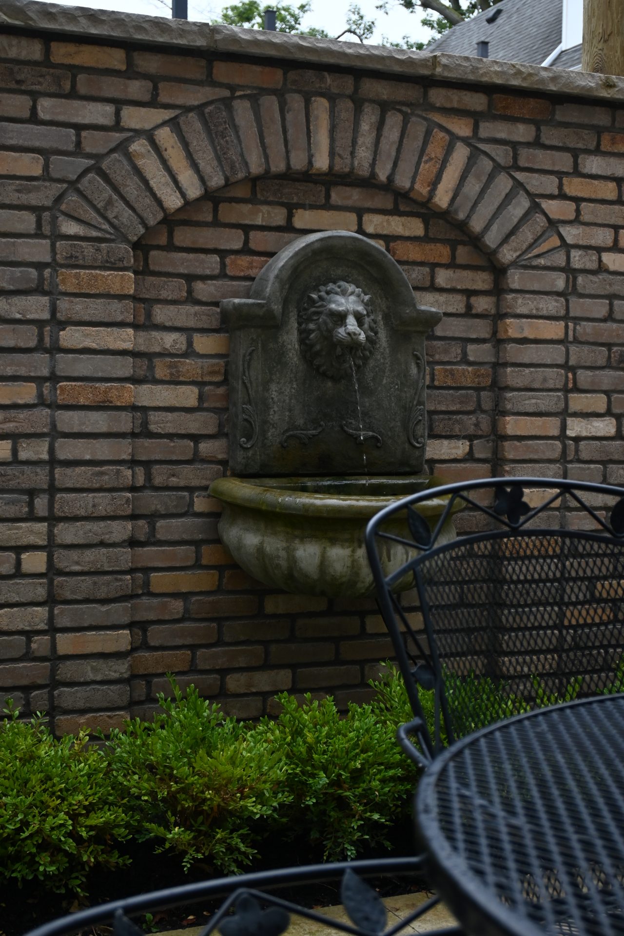 Stone lion head fountain on brick wall