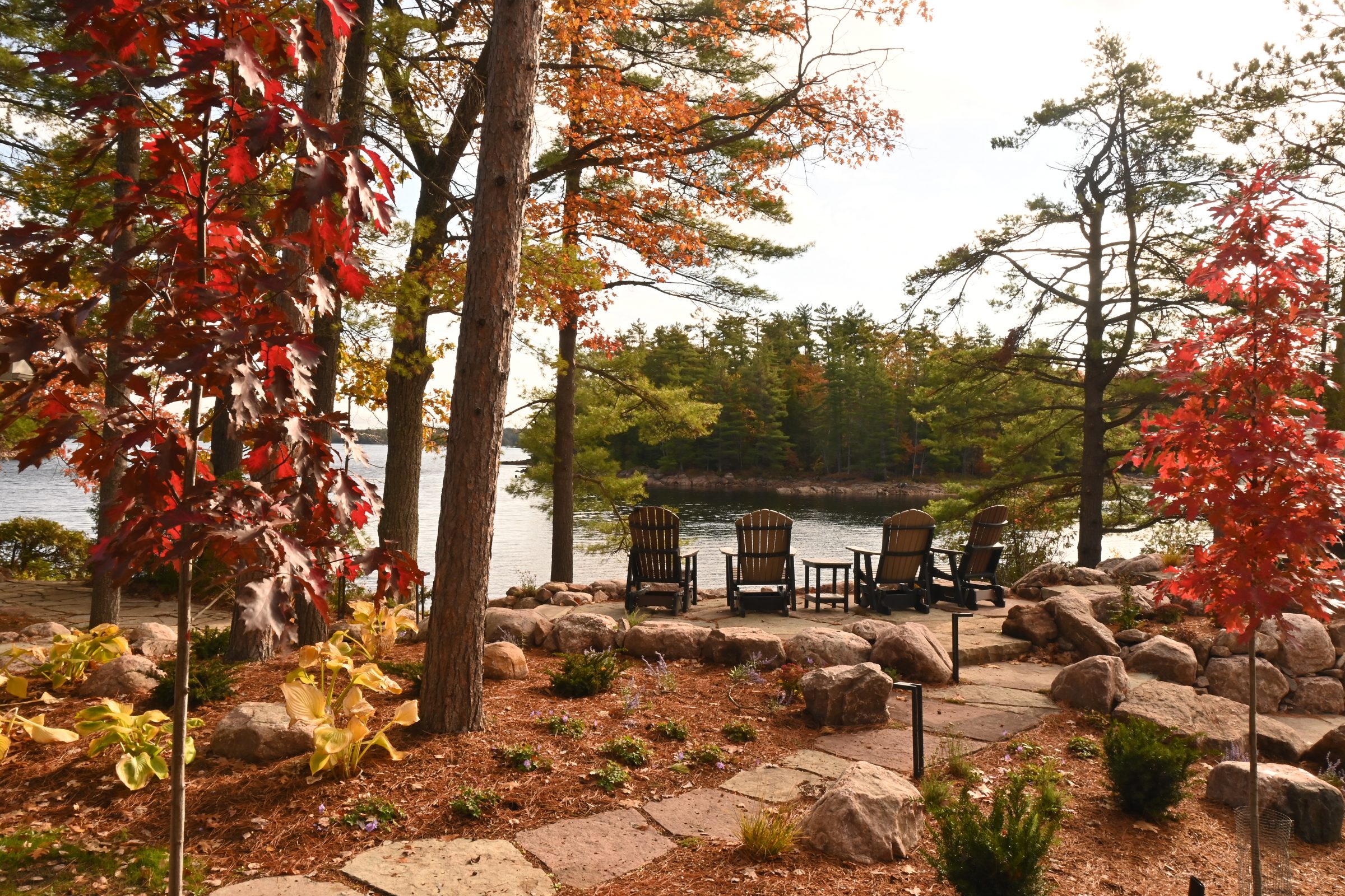 Chairs overlooking autumn lake, surrounded by colorful trees.