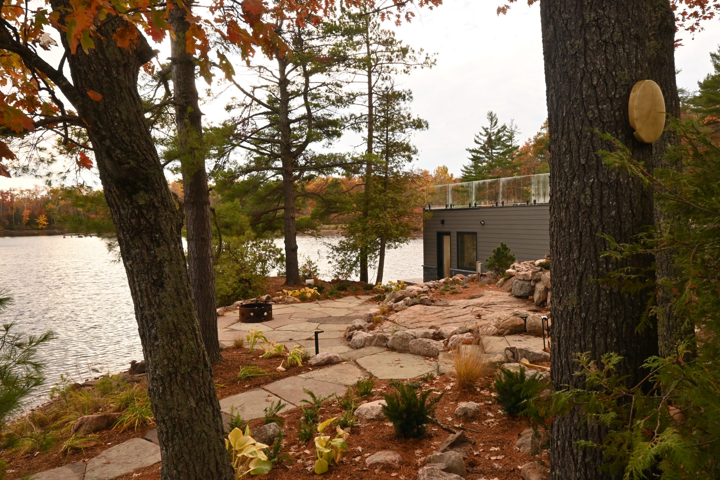 Lakeside cabin surrounded by autumn trees and rocks.