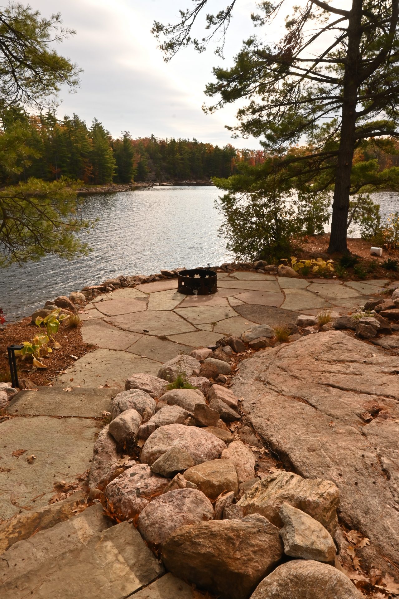 Stone patio by a lakeside with trees.