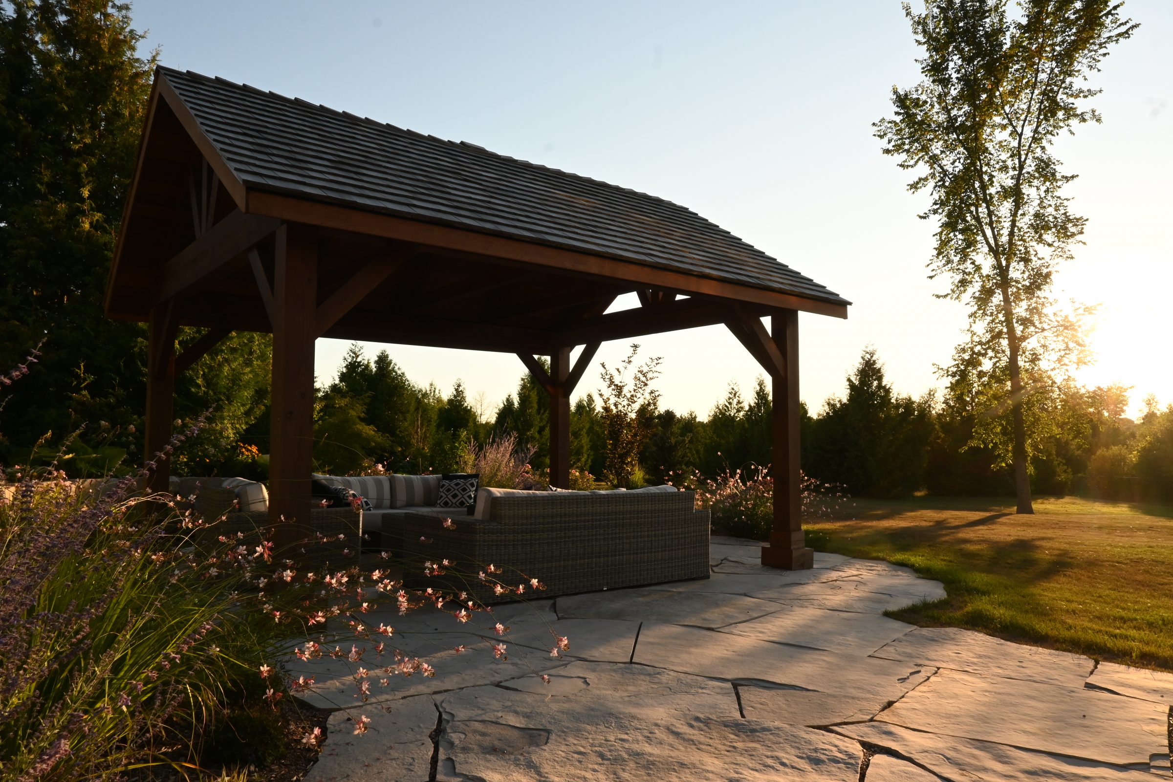 Garden patio with wooden gazebo at sunset.