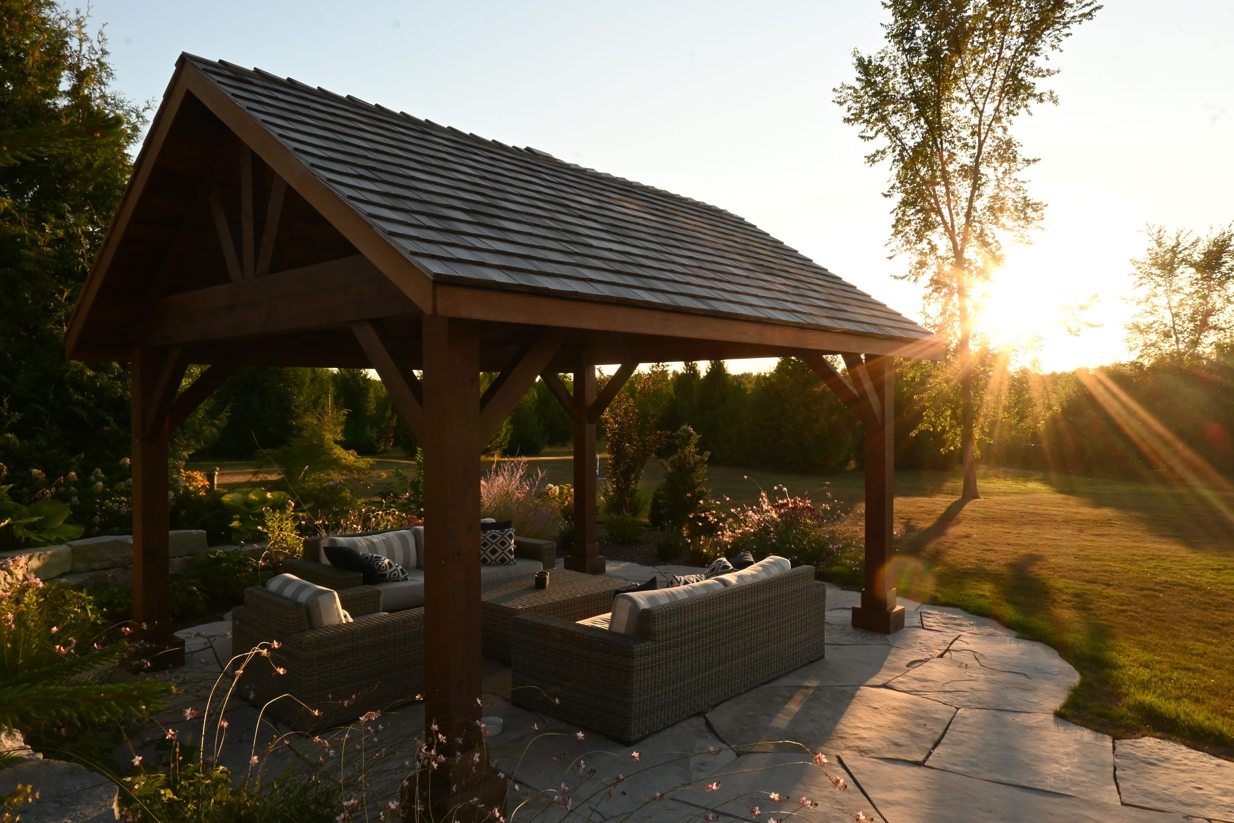 Wooden gazebo in sunny garden setting.