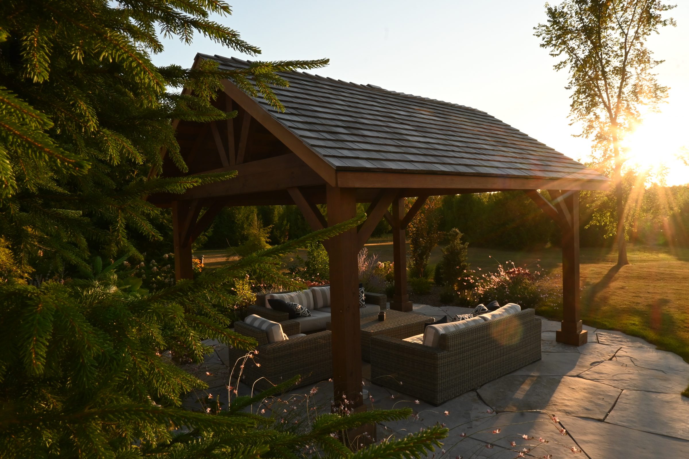 Cozy outdoor patio under wooden pergola at sunset.