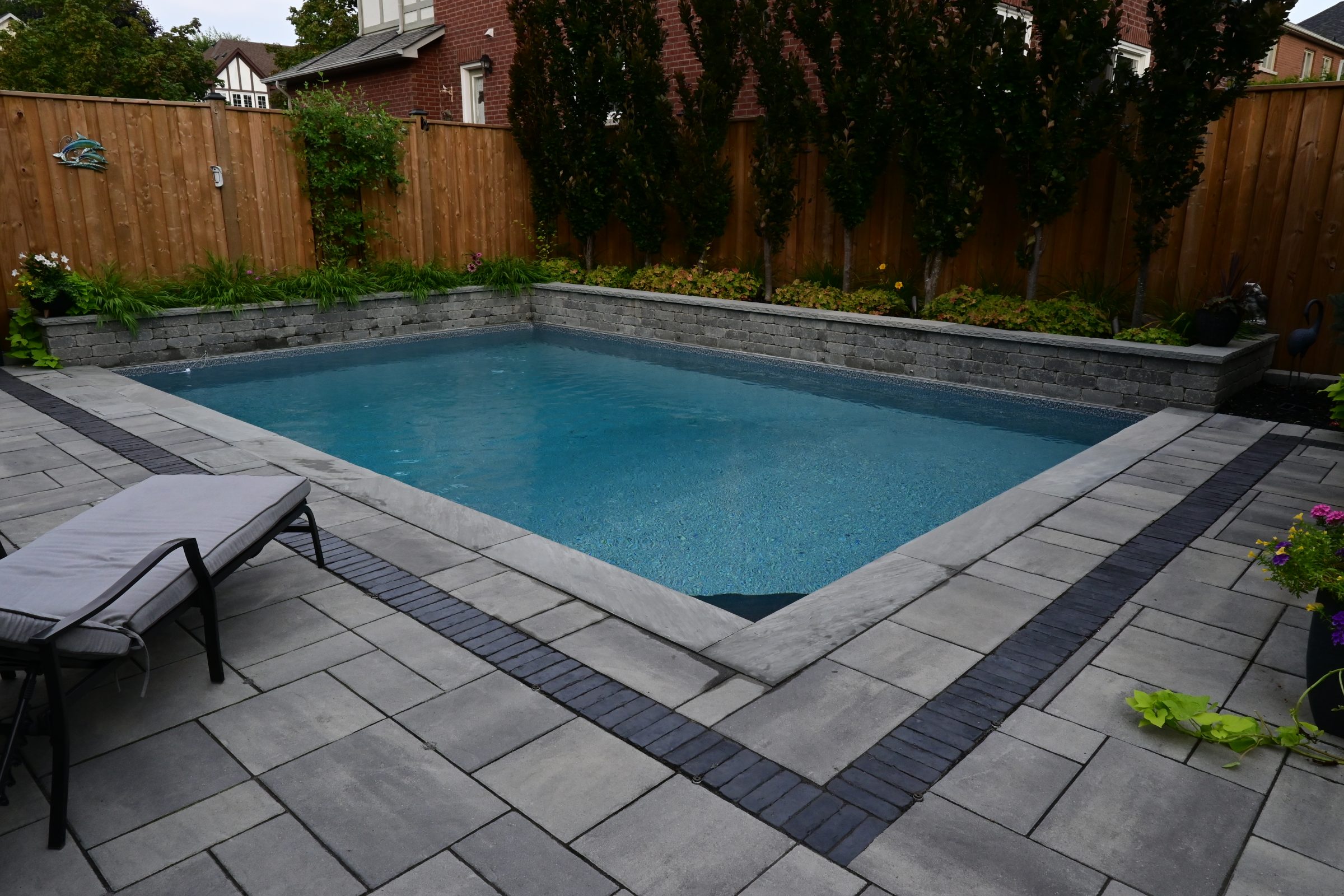 Backyard swimming pool with patio and plants.