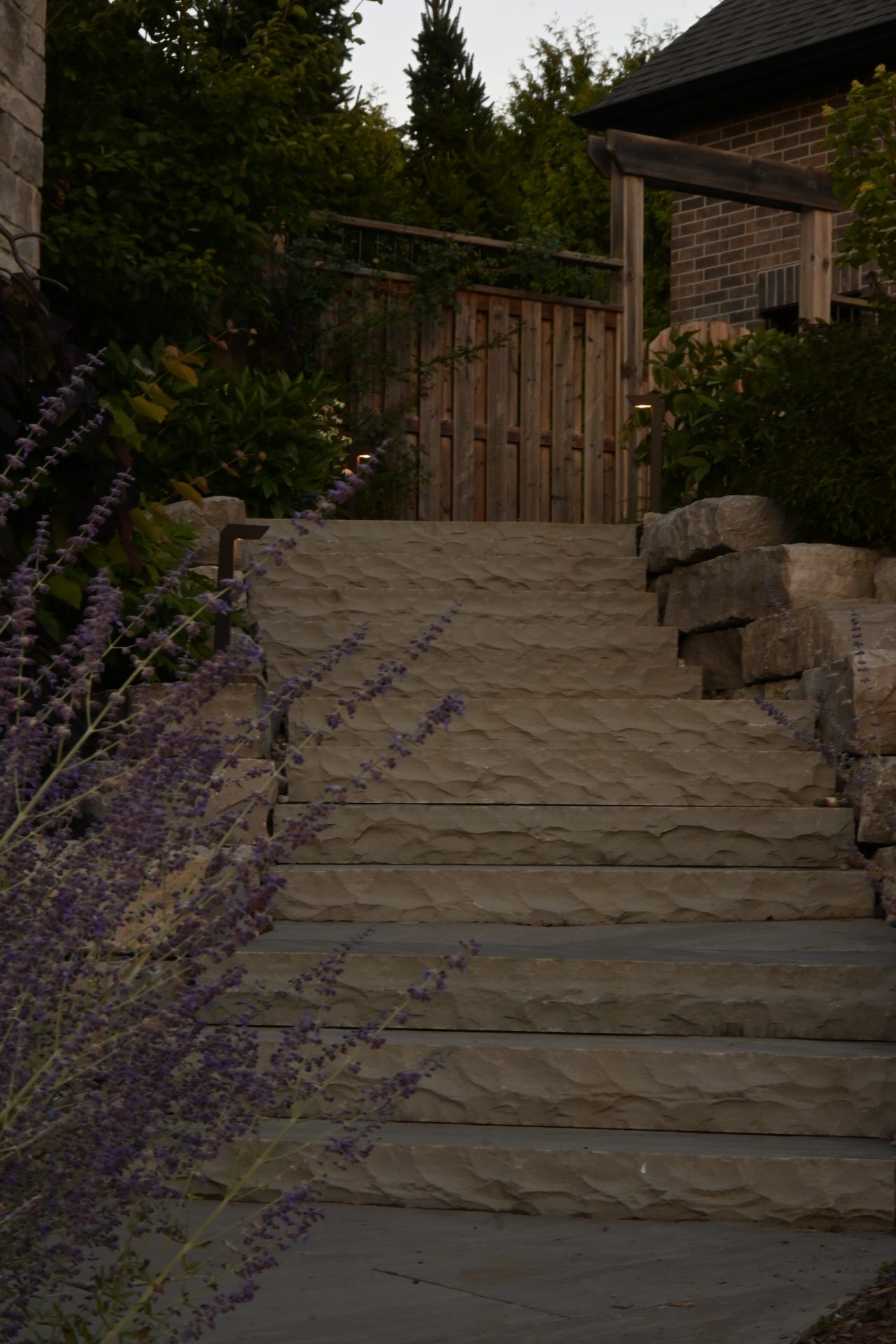 Stone garden stairs with plants and wooden gate.