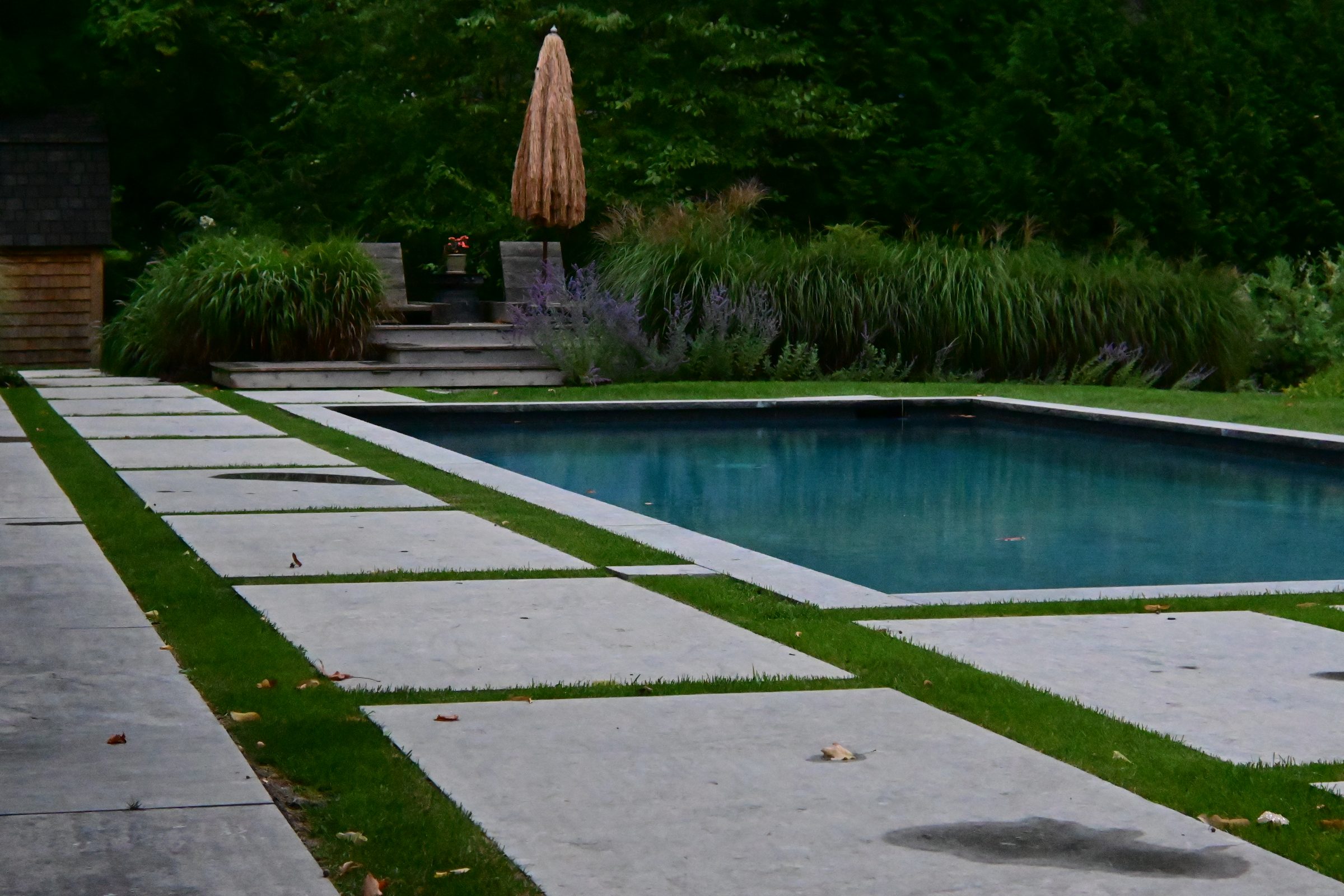 Modern pool with stone pathway and seating area.