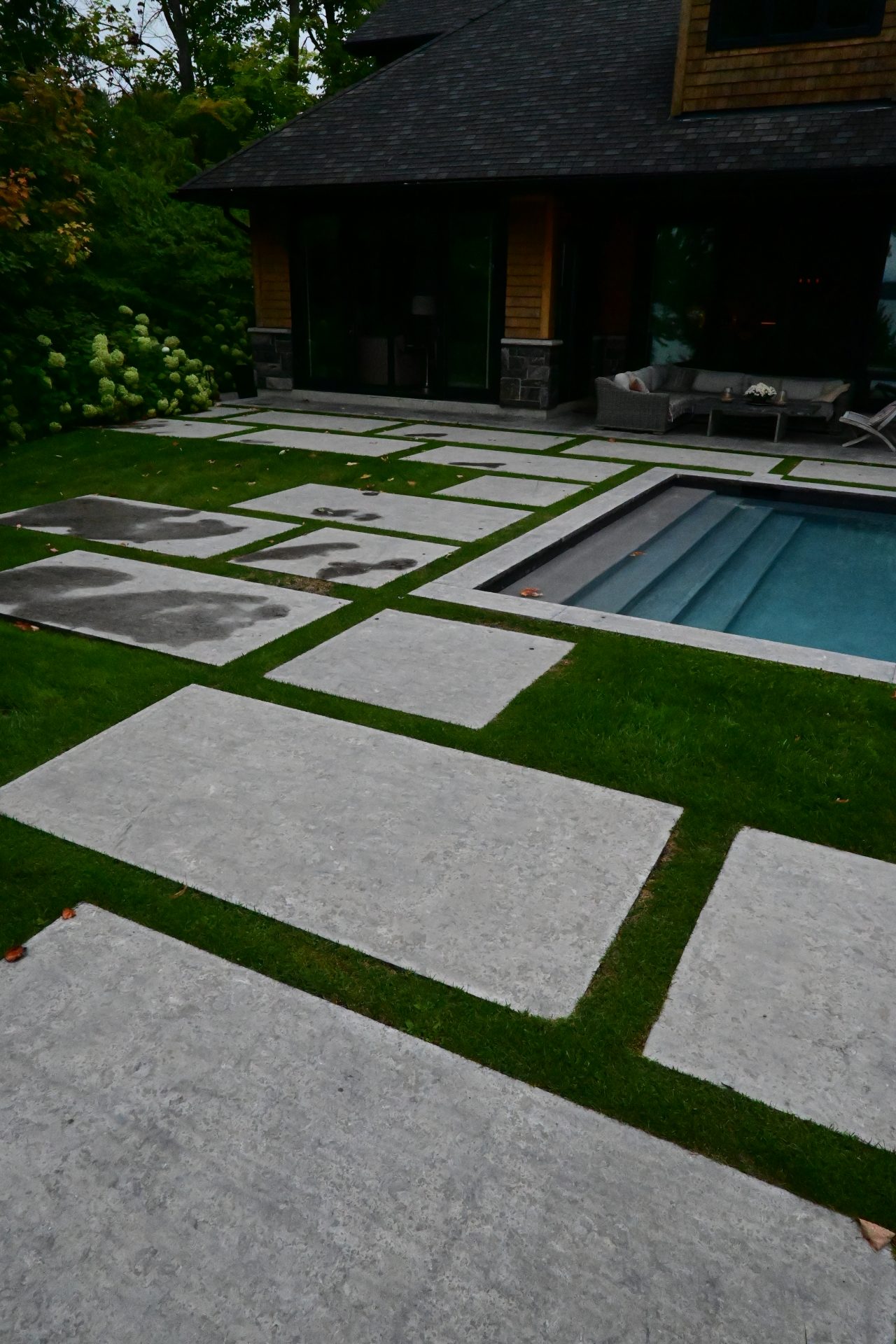 Modern backyard with paved walkway and pool.