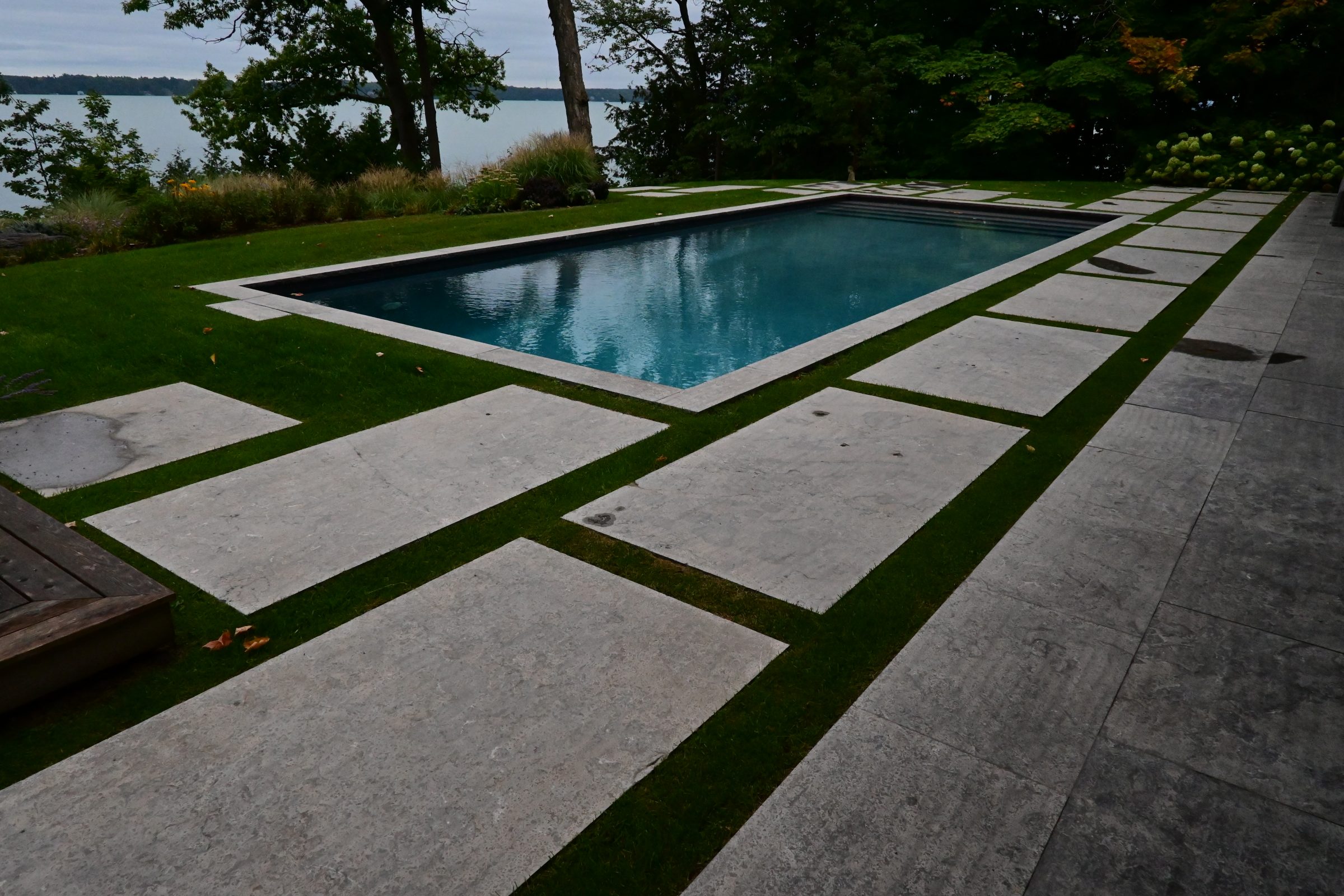 Outdoor pool with stone patio and lake view.