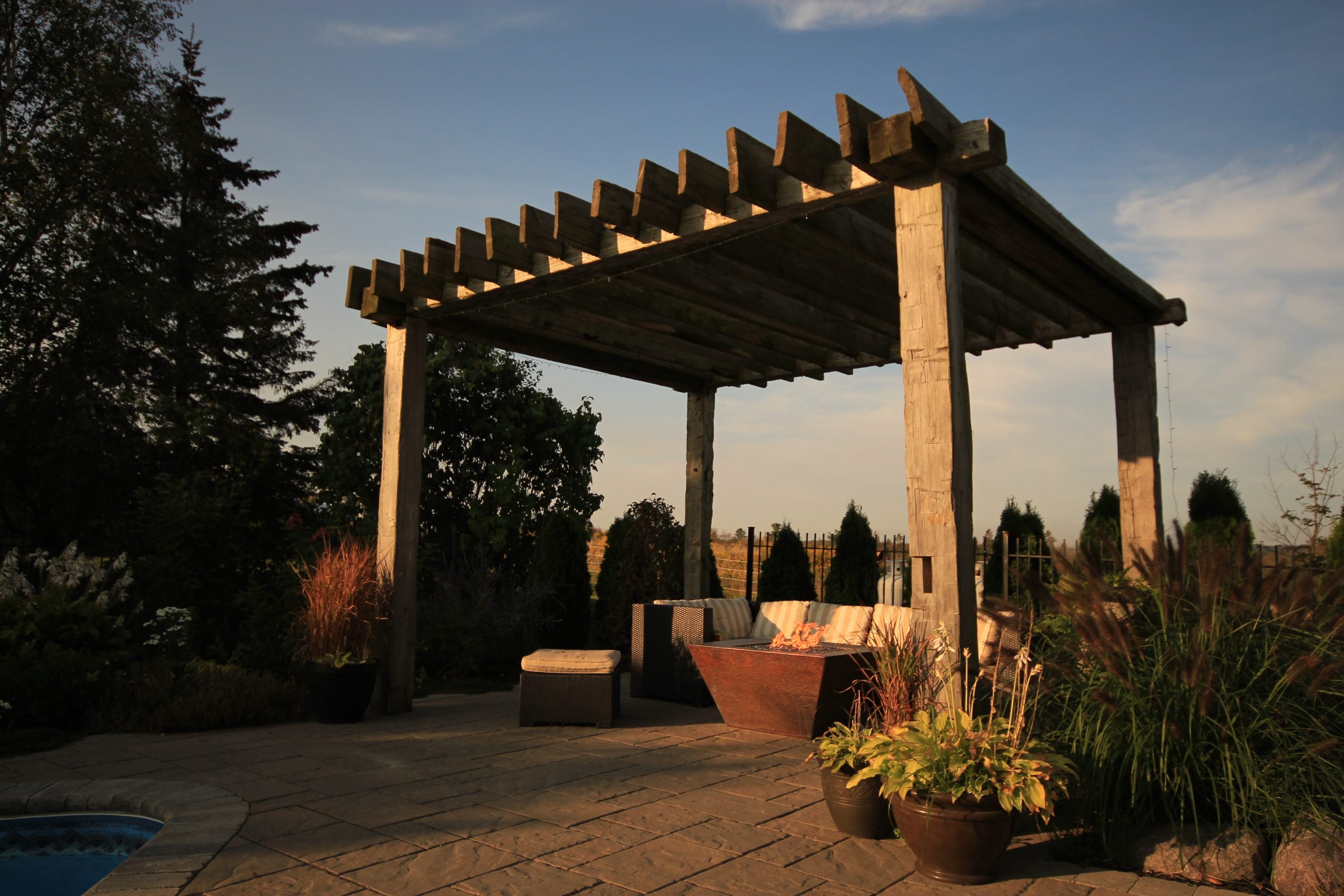 Outdoor patio with wooden pergola at sunset.