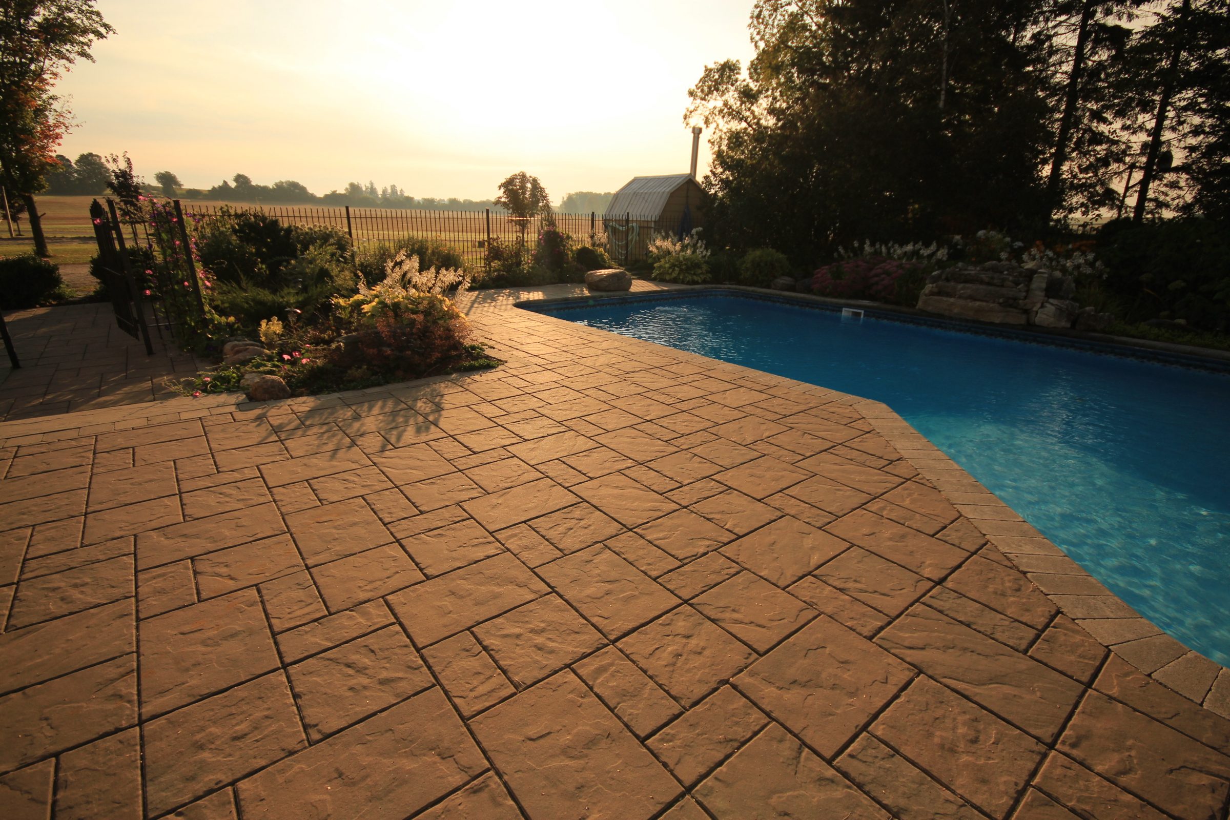 Sunlit patio with pool and garden view.