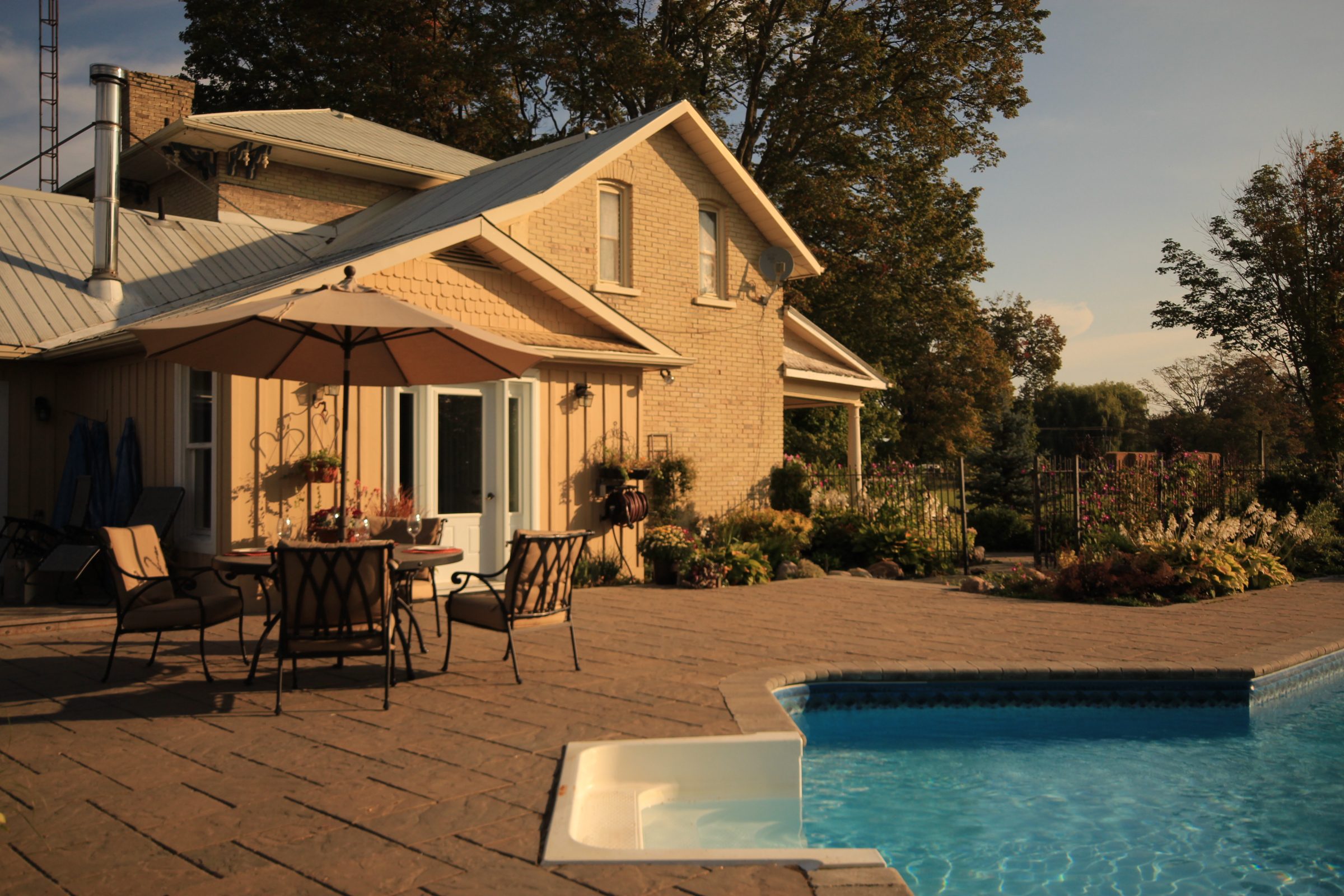 Sunlit patio with pool and umbrella set.