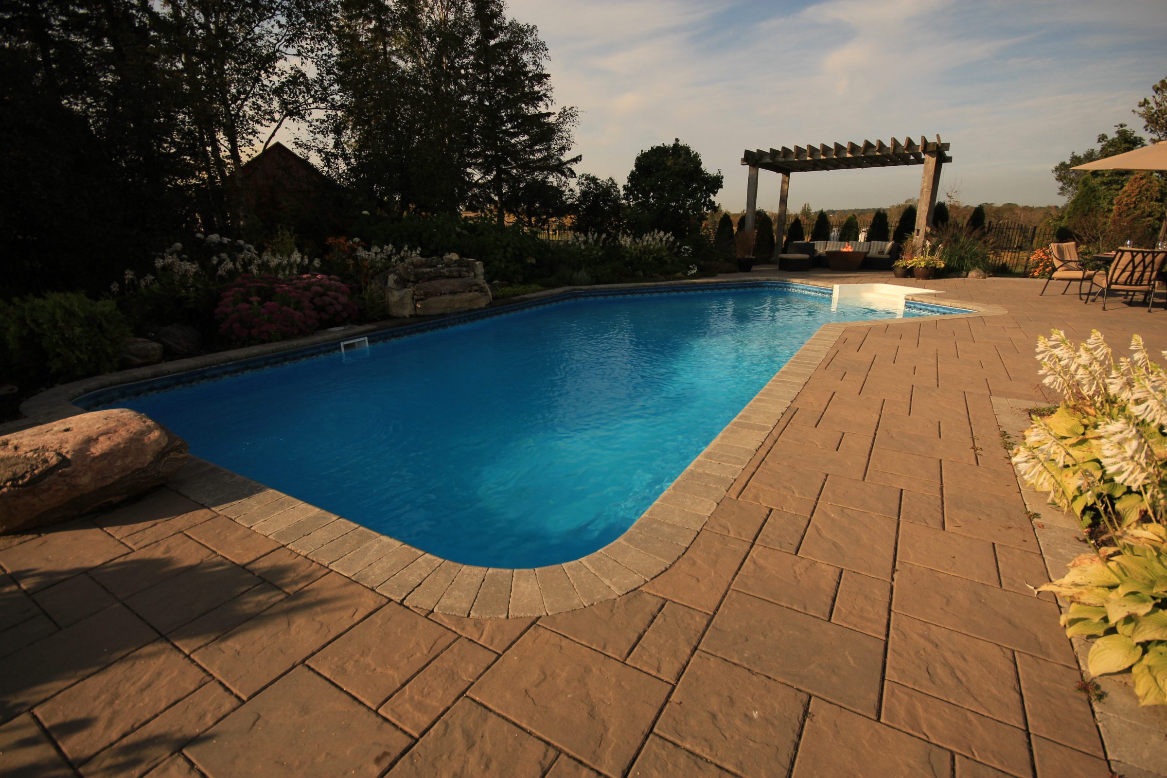 Backyard swimming pool with patio and garden.