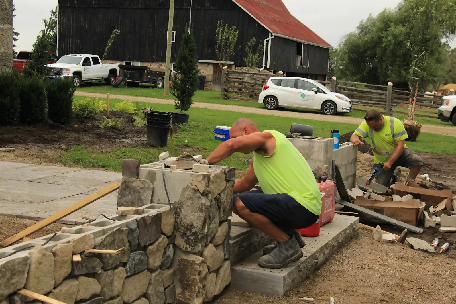 Construction workers building stone wall outdoors.
