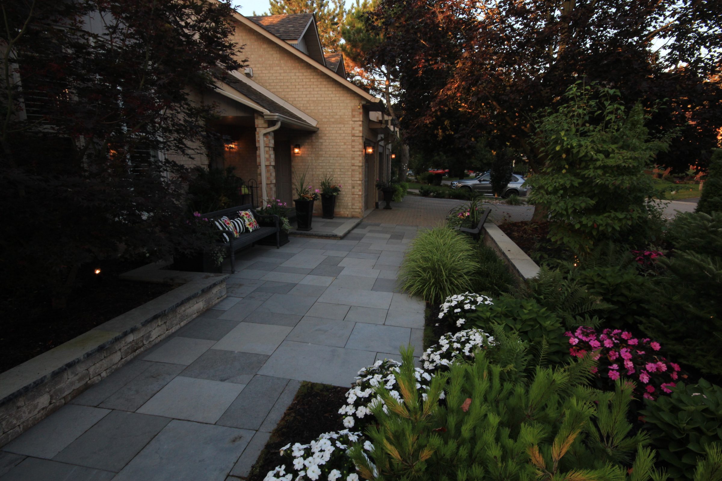 House entrance with garden and flowers at dusk.