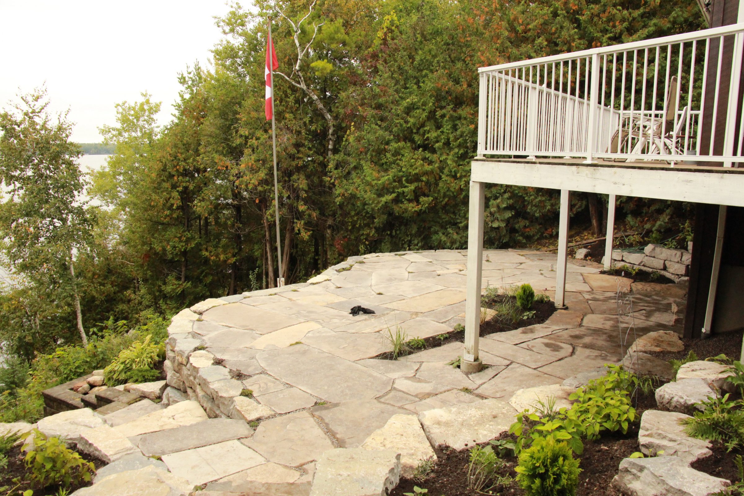 Stone patio with forest view and Canadian flag.