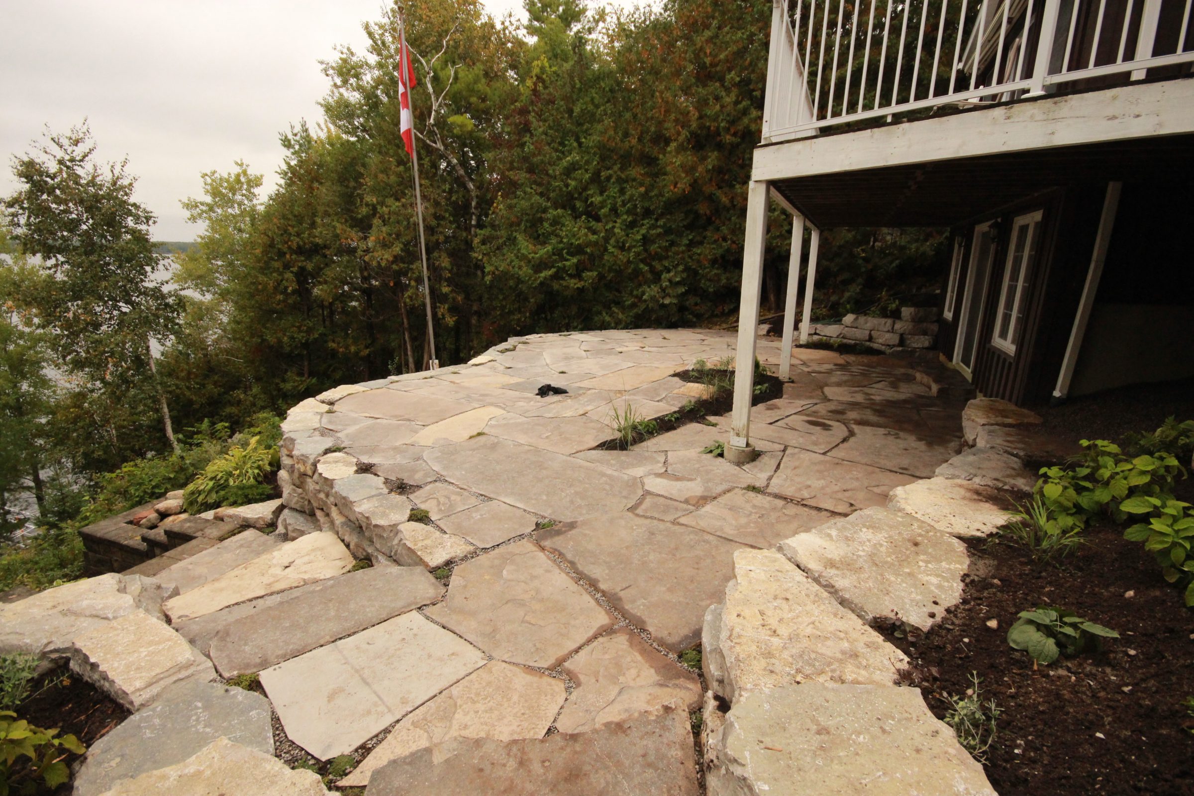Stone patio with Canadian flag and trees