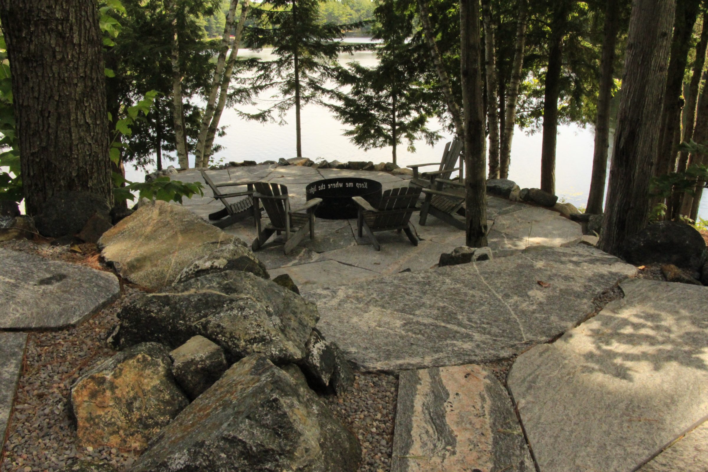 Stone fire pit with chairs by lake
