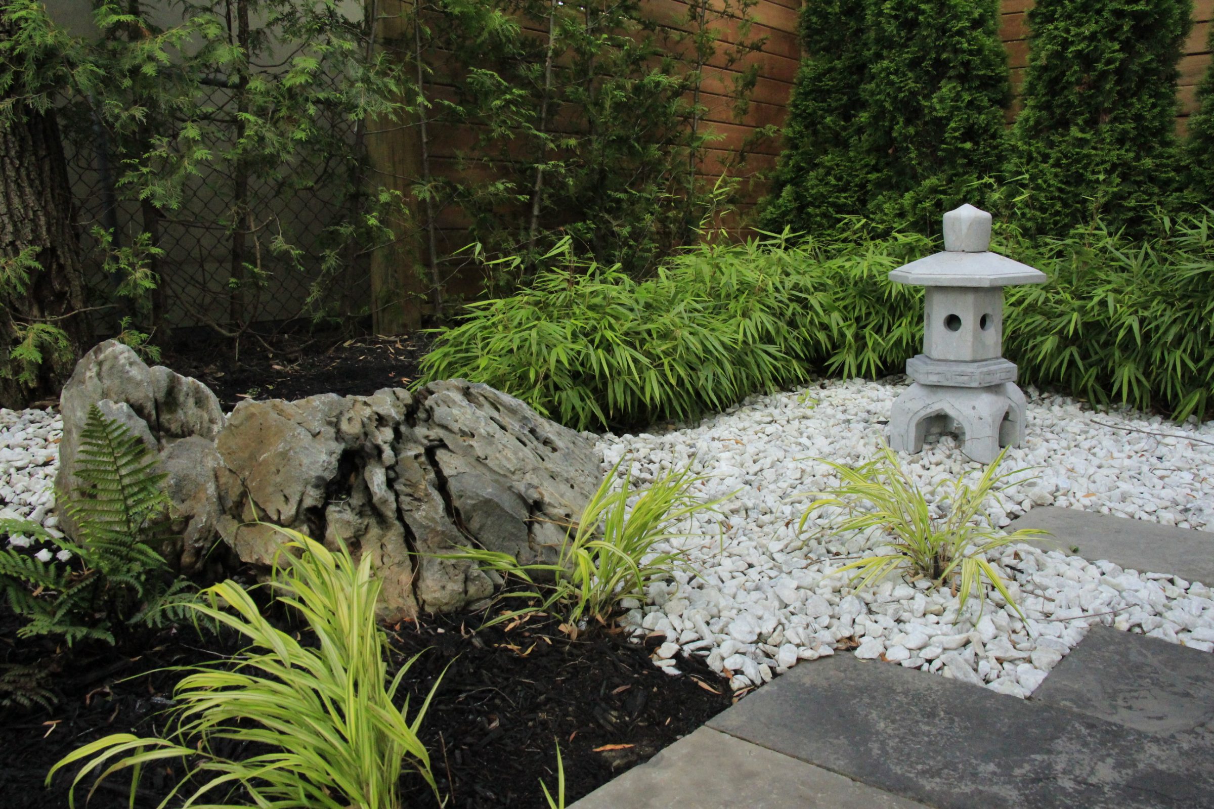 Serene Japanese rock garden with lantern and plants.