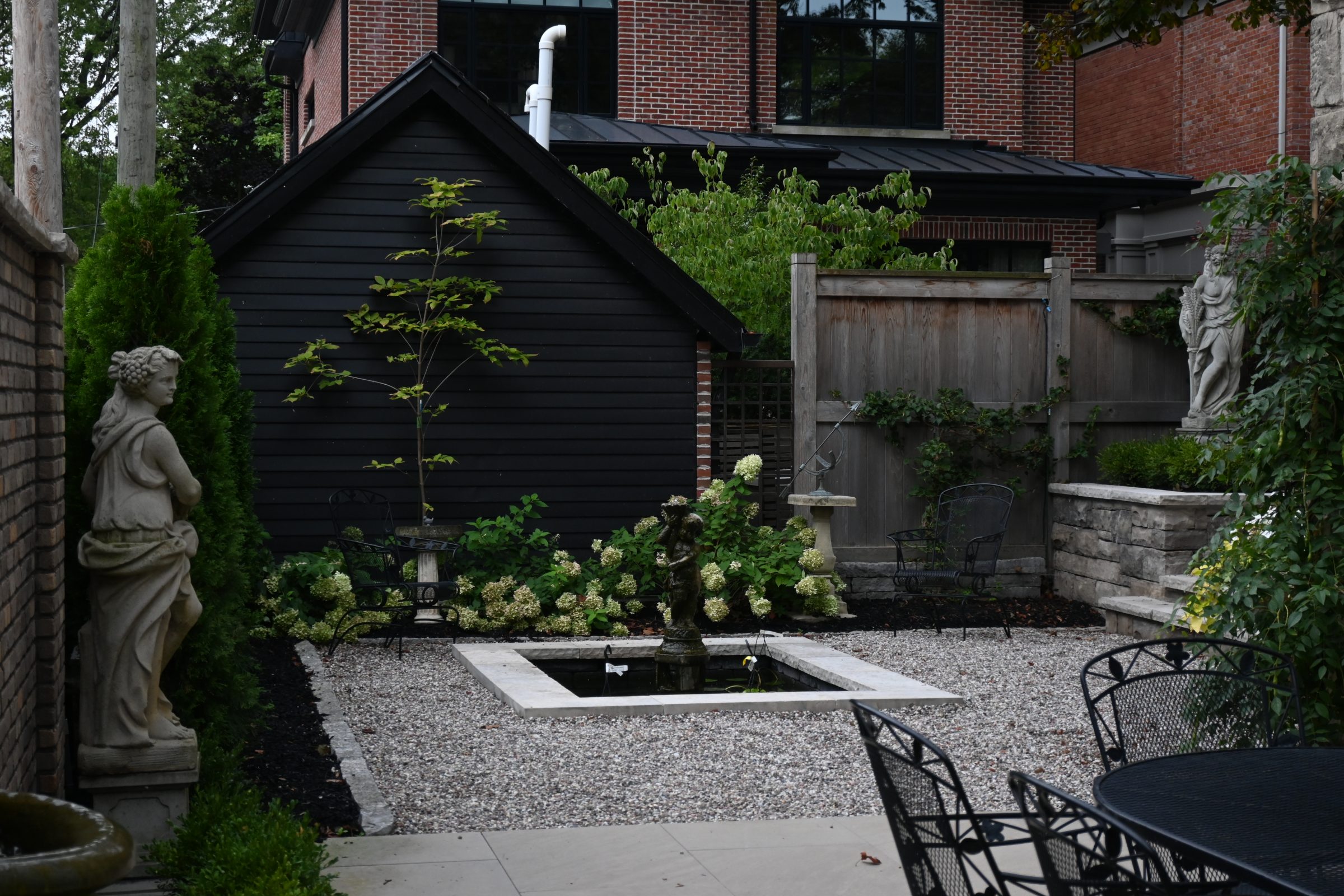 Garden with statues, plants, and a small pond.
